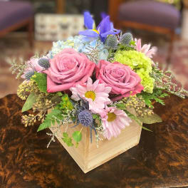 Pink roses and pastel mixed flowers arranged in a wooden box