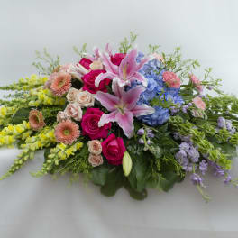 Low floral spray with pink lilies, roses, hydrangeas, and yellow blooms