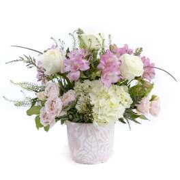 Arrangement of white roses, pink alstroemeria, blush spray roses, and hydrangeas in a patterned ceramic container