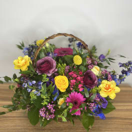 Colorful mixed flower basket with a woven handle