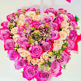Heart-shaped bouquet of pink and peach roses with small filler flowers