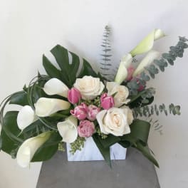 White calla lilies and roses with pink tulips in a white vase