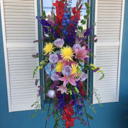 Tall standing floral spray with red, blue, purple, pink, and yellow blooms