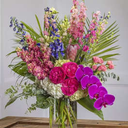 Tall mixed bouquet in a clear glass vase with pink, purple, and white flowers