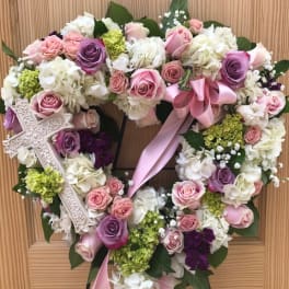 Heart-shaped floral wreath with pink and white roses and a ribbon bow