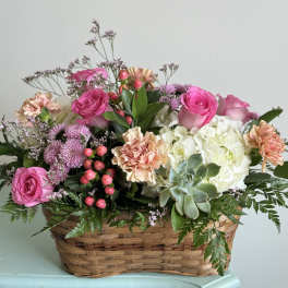 Basket arrangement of pink roses, carnations, hydrangea, and a succulent