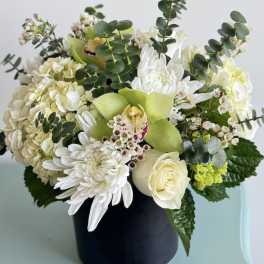 White and green floral arrangement in a black vase