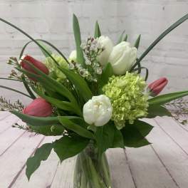 Tulips and hydrangea arranged in a clear glass vase