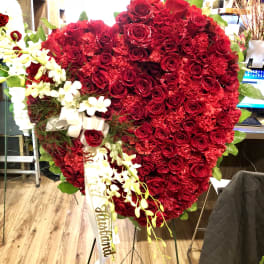Large heart-shaped red rose arrangement with white orchids and ribbon