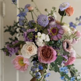 Handheld bouquet of pastel mixed flowers in pink, purple, white, and blue