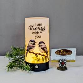 Lit memorial candle with two birds and the words "I am always with you"