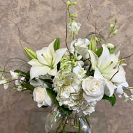 White lilies and roses arranged in a clear glass vase