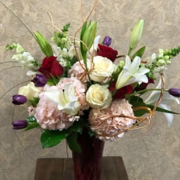 Bouquet of roses, lilies, and hydrangeas in a red vase