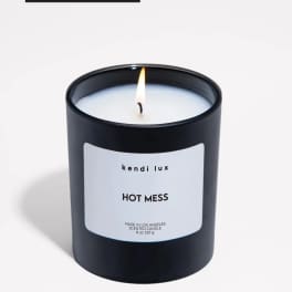 Lit black scented candle in a glass jar with a white label