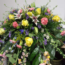 Large mixed floral arrangement with yellow roses, lilies, and pink carnations