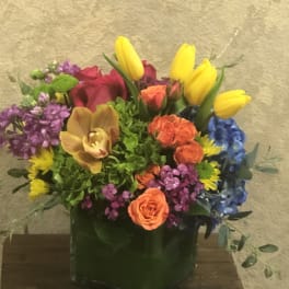 Colorful mixed flower arrangement in a square glass vase