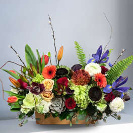 Mixed floral arrangement in a wooden box with bright blooms and branches