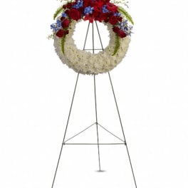 Standing floral wreath with red, white, and blue flowers on an easel
