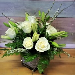 White roses and lilies arranged in a square vase