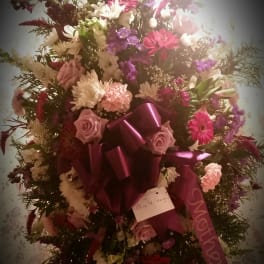 Large standing floral spray with pink, white, and purple blooms and a magenta ribbon