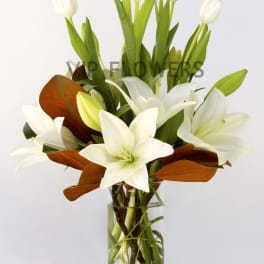 White lilies and tulips in a clear glass vase