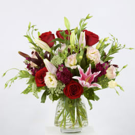 Bouquet of red roses and pink lilies in a clear glass vase