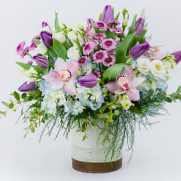 Purple tulips and pink orchids in a white vase