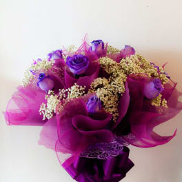 Purple roses with white filler flowers wrapped in magenta paper