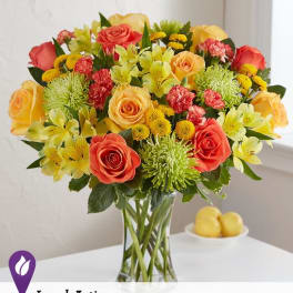 Mixed bouquet of roses, lilies, and mums in a glass vase