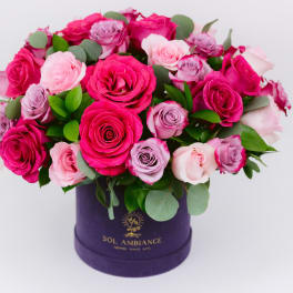 Pink and lavender roses arranged in a purple hat box