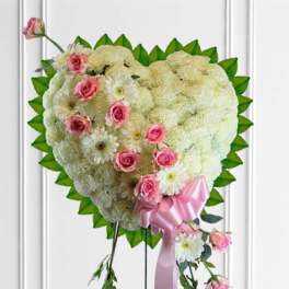 Heart-shaped floral spray with pink roses, white flowers, and a pink ribbon
