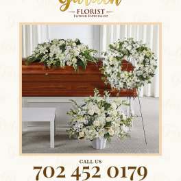 White funeral floral arrangements with a casket spray and standing wreath.