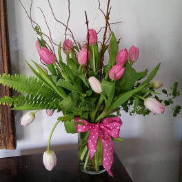 Pink and white tulips in a clear glass vase with a pink polka-dot bow