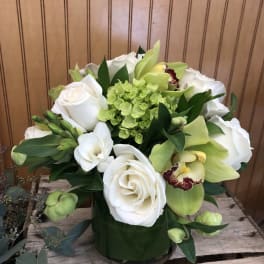White roses and green orchids in a glass vase