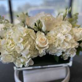 Cream hydrangeas and white roses in a low rectangular arrangement