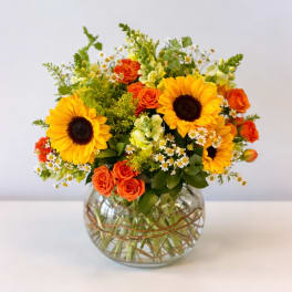 Sunflower and orange rose arrangement in a round glass vase