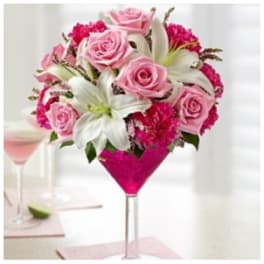 Pink roses and white lilies arranged in a martini glass vase