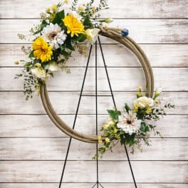 Floral wreath with yellow and white flowers on a black stand