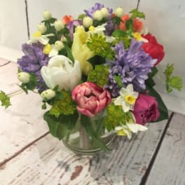 Colorful mixed bouquet with tulips, hyacinths, and daffodils in a clear glass vase