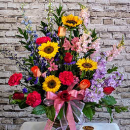 Colorful mixed flower arrangement in a vase with a pink ribbon