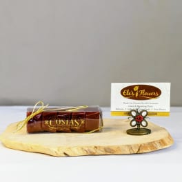 Wood slab display with wrapped chocolates and a florist business card in a small flower-shaped holder.