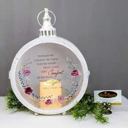 Decorative memorial lantern with a candle and floral accents