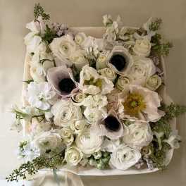 White floral bouquet with pale pink anemones and roses in a square wrap