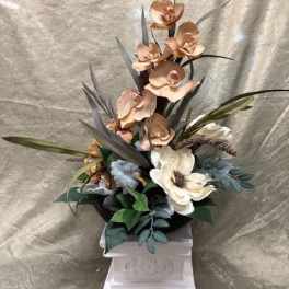 Tall floral arrangement with orchids and a white bloom in a pedestal vase