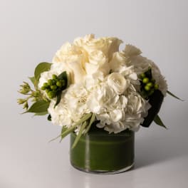 White rose and hydrangea bouquet in a green glass vase