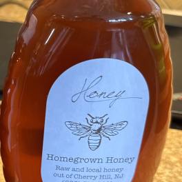 Bottle of honey with a white cap and labeled front