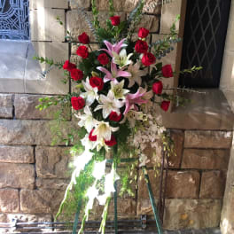 Standing floral spray with red roses and white lilies on a metal easel