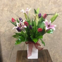 Bouquet of pink, purple, and white lilies in a white vase