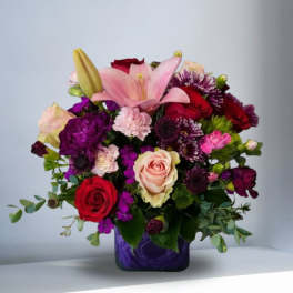 Mixed bouquet with pink lilies, red and blush roses in a purple vase