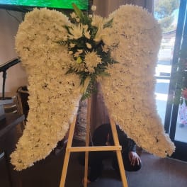 Large white floral standing spray on an easel in a wing shape